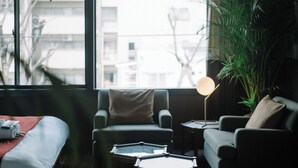 A modern living room with a sofa, armchairs, a coffee table, and a large window with a view of buildings.