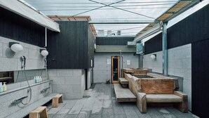 A modern bathroom with a stone floor, wooden benches, and a large bathtub.