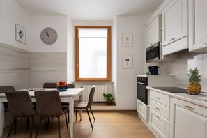 A modern kitchen with white cabinets, a microwave, stove, and a pineapple on the counter.