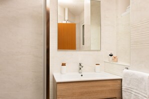 A modern bathroom with a white sink, wooden vanity, and a large mirror.