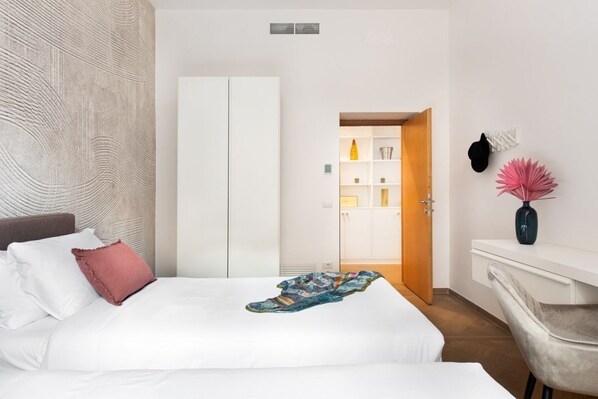 A bedroom with a bed, a wardrobe, a desk, and a chair.