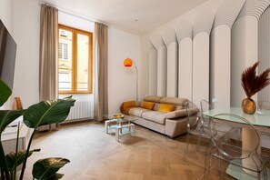 A modern living room with a sofa, glass coffee table, and clear chairs.
