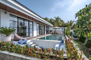 A modern poolside area with a white building, large windows, and a swimming pool. - Jing Jang Villa Ungasan (Kutuh)