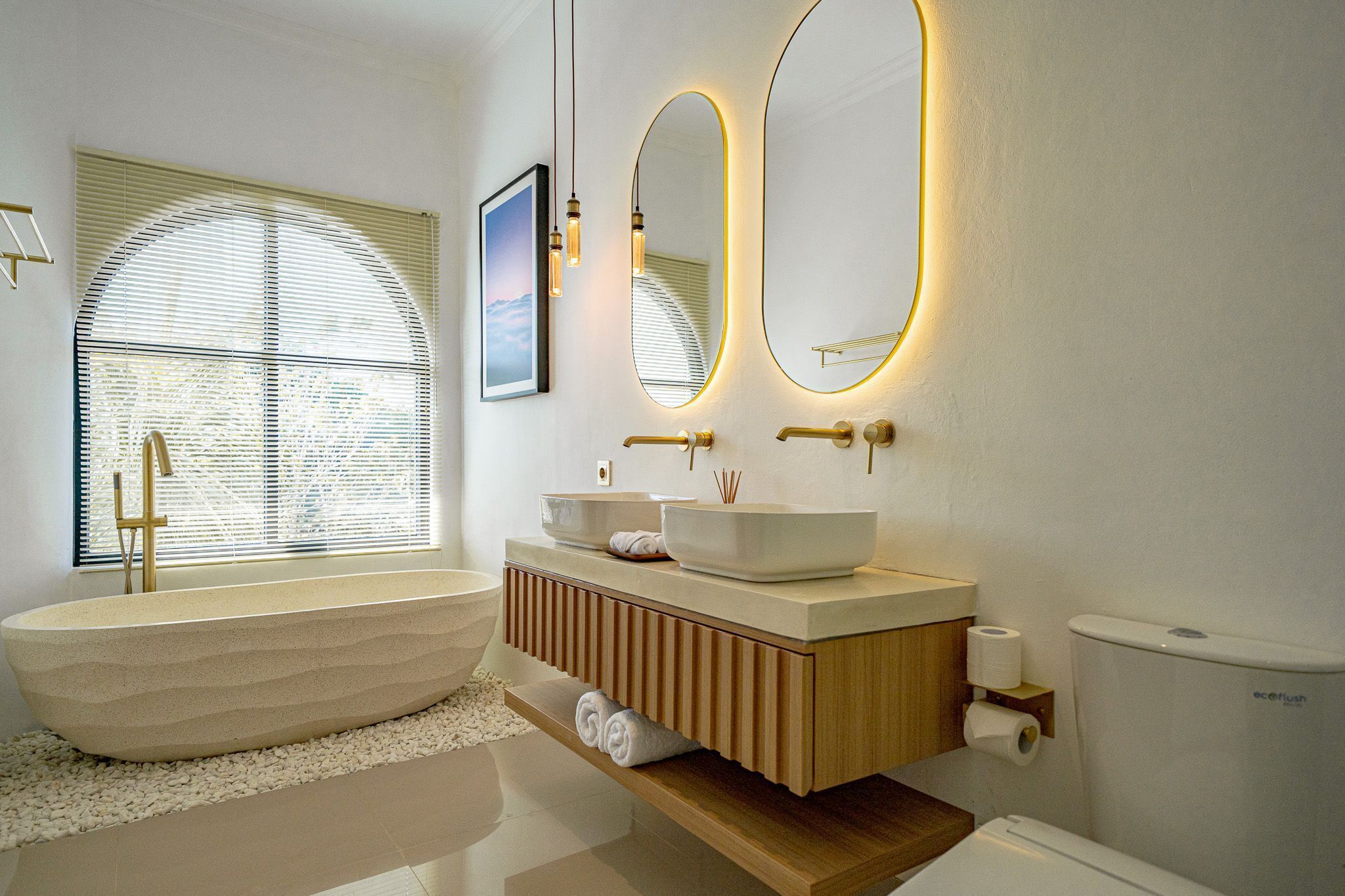 A modern bathroom with a freestanding bathtub, a vanity with a sink, and two wall mirrors.