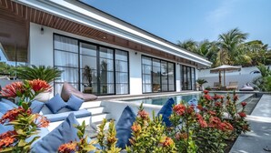 Ein modernes Haus mit Swimmingpool, großen Fenstern und Sitzgelegenheiten im Freien.