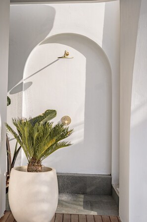 A potted plant in a white pot, a concrete bench, and a white wall with a curved archway. - Jing Jang Villa Ungasan (Kutuh)