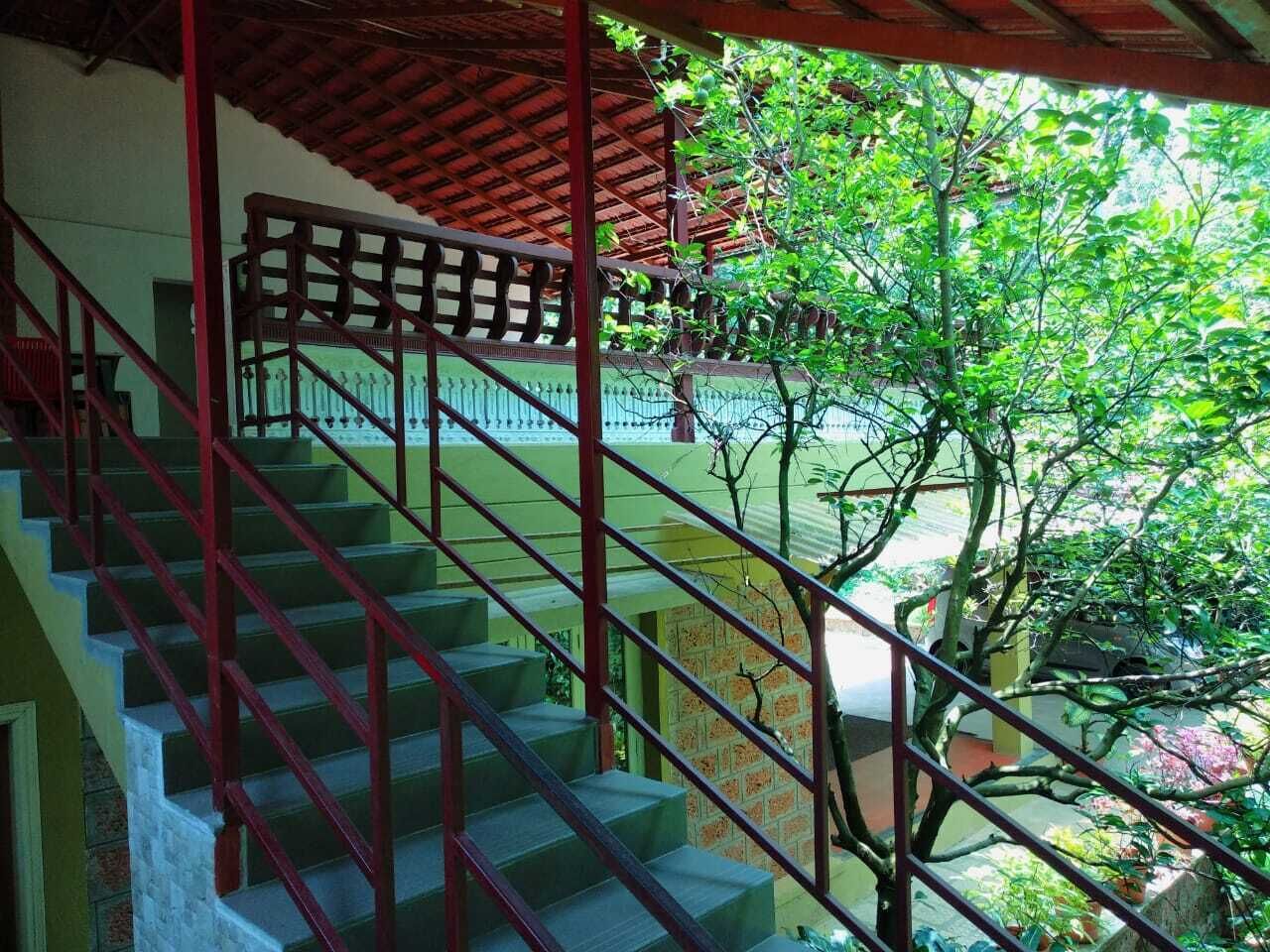 A staircase with red railings leading to a covered area with a view of greenery.