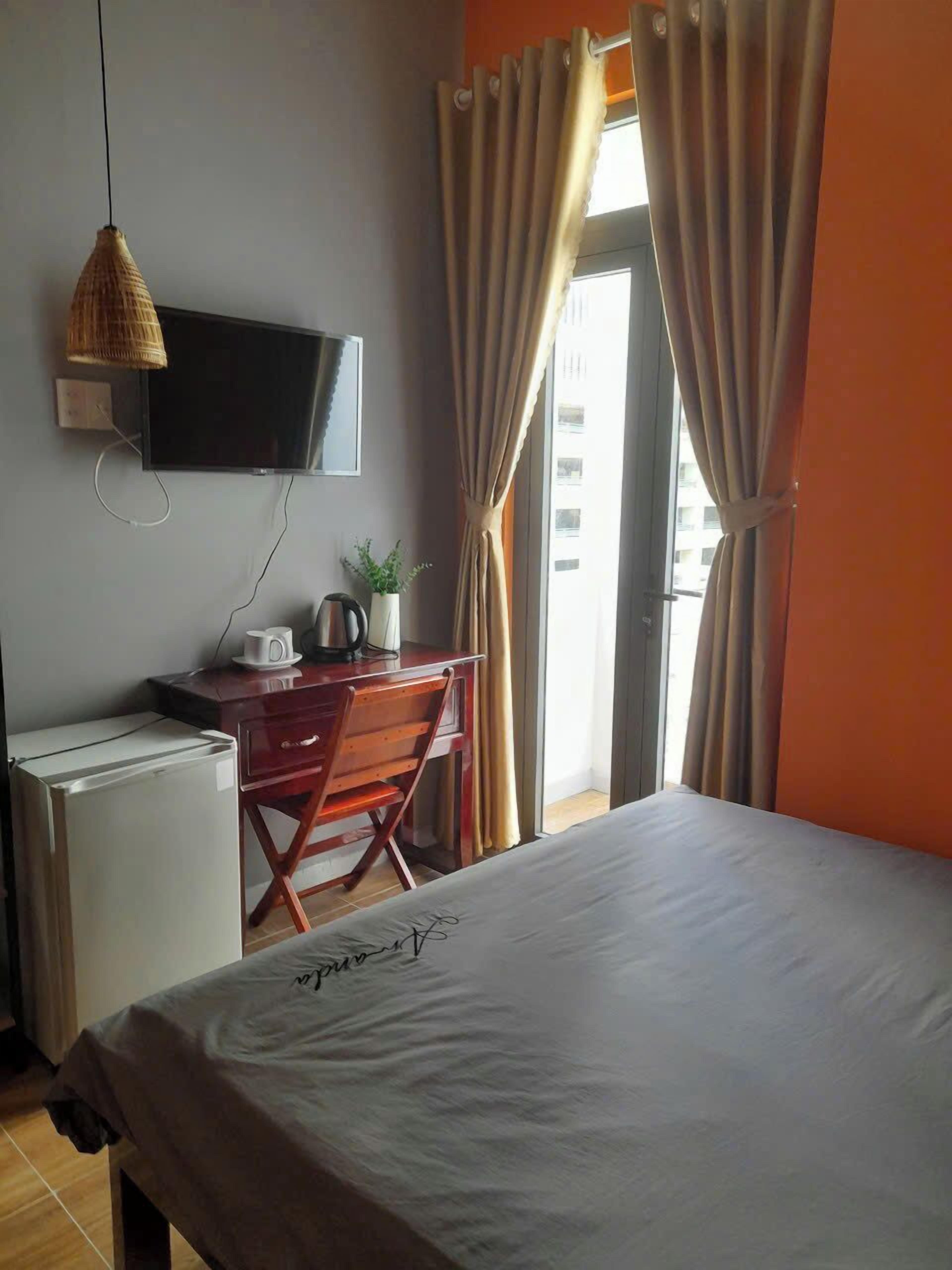 Une chambre d’hôtel équipée d’un lit, d’un bureau avec un ordinateur, d’une télévision et d’un petit réfrigérateur.