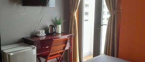 Une chambre d’hôtel équipée d’un lit, d’un bureau avec un ordinateur, d’une télévision et d’un petit réfrigérateur.