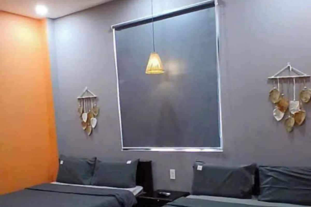 Une chambre avec deux lits, un luminaire suspendu et des éléments décoratifs sur les murs.