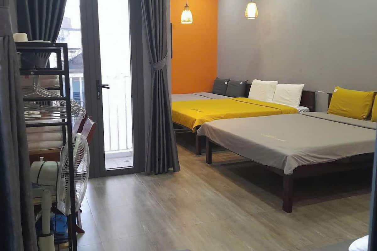 Une chambre d’hôtel avec un lit, un canapé, un ventilateur et une fenêtre avec des rideaux.