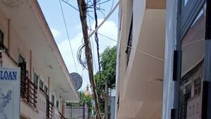 Ένα στενό σοκάκι με κτίρια και στις δύο πλευρές, μια μοτοσικλέτα παρκαρισμένη στην αριστερή πλευρά και μια μεταλλική πύλη στο κέντρο.