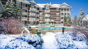 A multi-story hotel with balconies, a swimming pool, and snow-covered surroundings. - Allegheny Springs 414: Junior Studio Slopeside (Snowshoe)