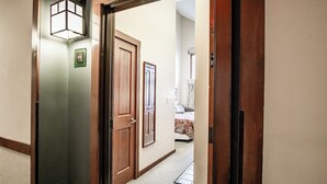 A hallway with wooden doors, a carpeted floor, and a light fixture on the wall. - Allegheny Springs 414: Junior Studio Slopeside (Snowshoe)