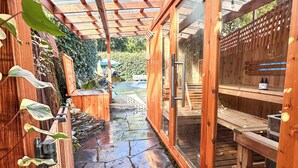 Una terraza de madera con un sendero de piedra que conduce a un porche con paredes de vidrio.