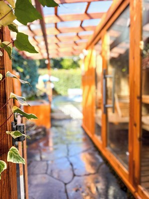 A wooden pergola with climbing plants, a stone pathway, and a glass door leading to a room. - The Resort at Benbow- Private Spa, Comforts of home (Garberville)