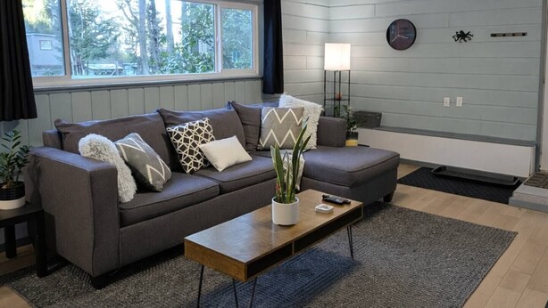 A modern living room with a grey sofa set, a coffee table, and a lamp. - Comfortable Home in the Comox Valley (Comox)