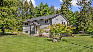 A two-story house with a grey exterior, a small porch, and a well-maintained lawn. - Comfortable Home in the Comox Valley (Comox)