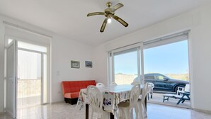 A dining area with a table and chairs, a red sofa, and a ceiling fan. - La Torre by Interhome (Ugento)