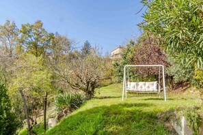 Un jardín con un columpio, un sendero cubierto de césped y un edificio al fondo.