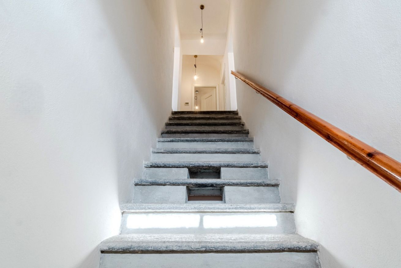 A staircase with a wooden handrail leading to a room with a door at the top.