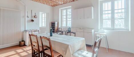 A spacious room with a brick ceiling, white walls, and large windows.