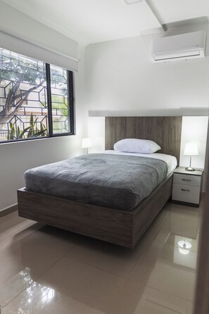 Relax in a serene space with a large bed, two bedside tables, and a window offering a view of the outdoors.