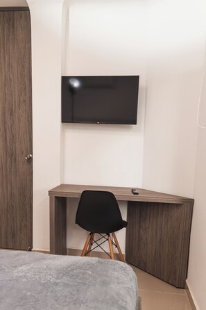 Cozy retreat with a neatly made bed, desk, and mounted TV.