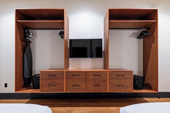 A modern room with a wooden wardrobe, a flat-screen TV, and a small seating area.