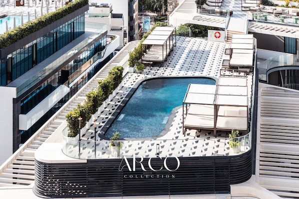 A rooftop pool with lounge chairs and a sign for ARCO COLLEGE.
