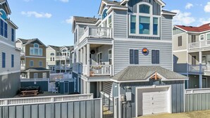 A multi-story residential building with a garage, a balcony, and a small porch area. - CB49 - Cruisin' The Dunes, Gated Corolla Townhome w/ Hot Tub & Resort Pool (Corolla)