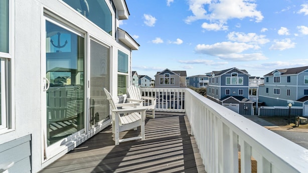 A wooden deck with white chairs and a glass door leading to a covered area. - CB49 - Cruisin' The Dunes, Gated Corolla Townhome w/ Hot Tub & Resort Pool (Corolla)