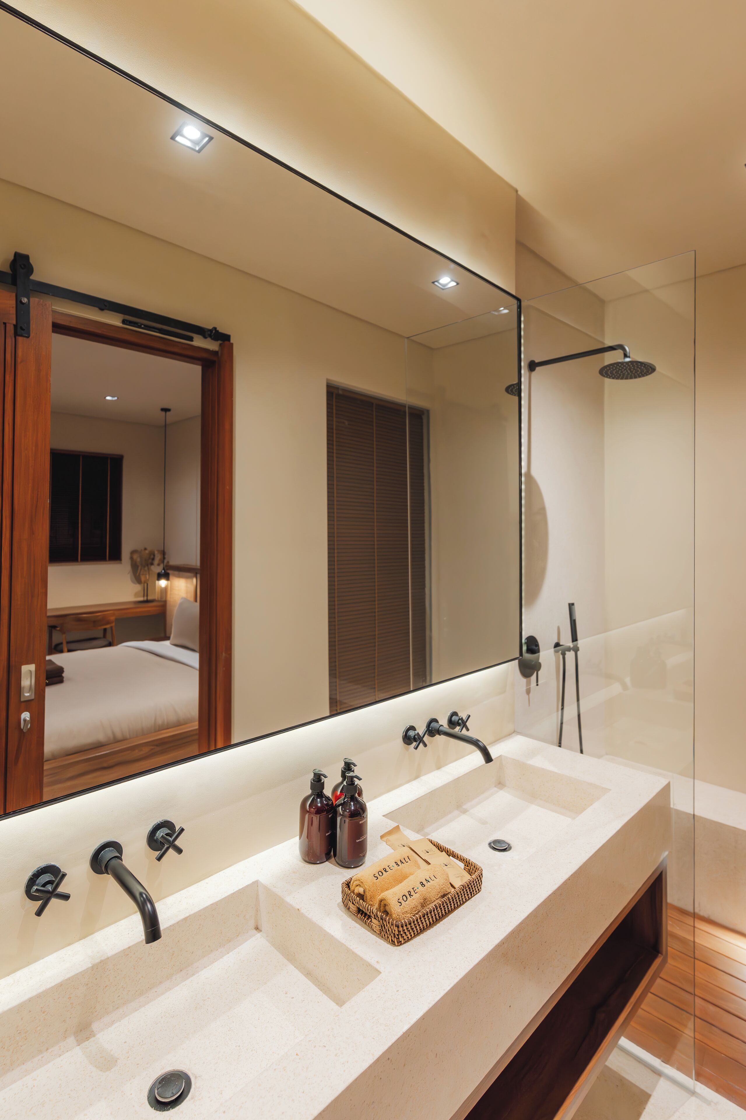 Une salle de bain moderne avec un grand miroir, deux vasques et une douche.
