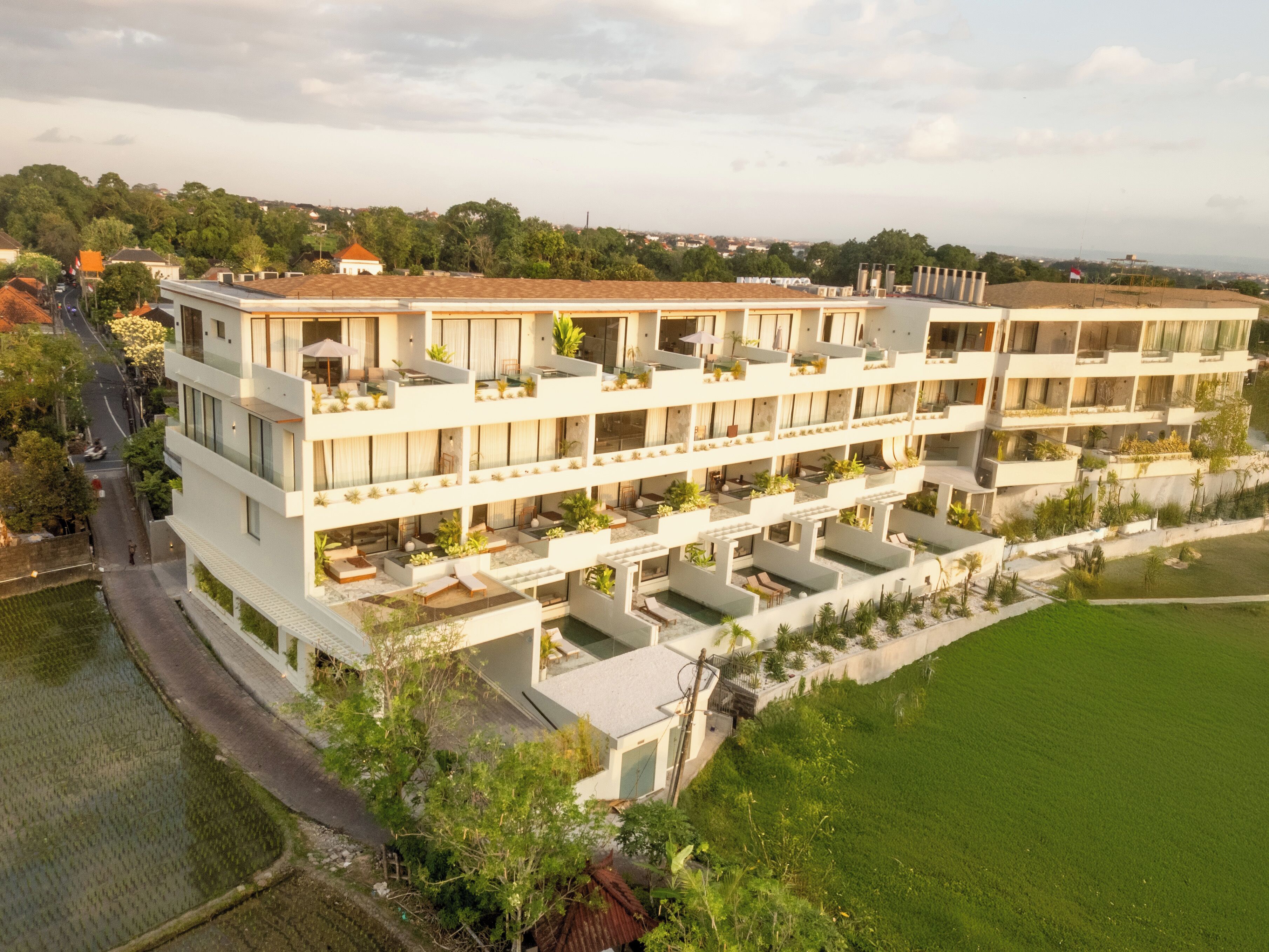 A multi-story hotel with balconies, outdoor seating, and a view of the surrounding area.