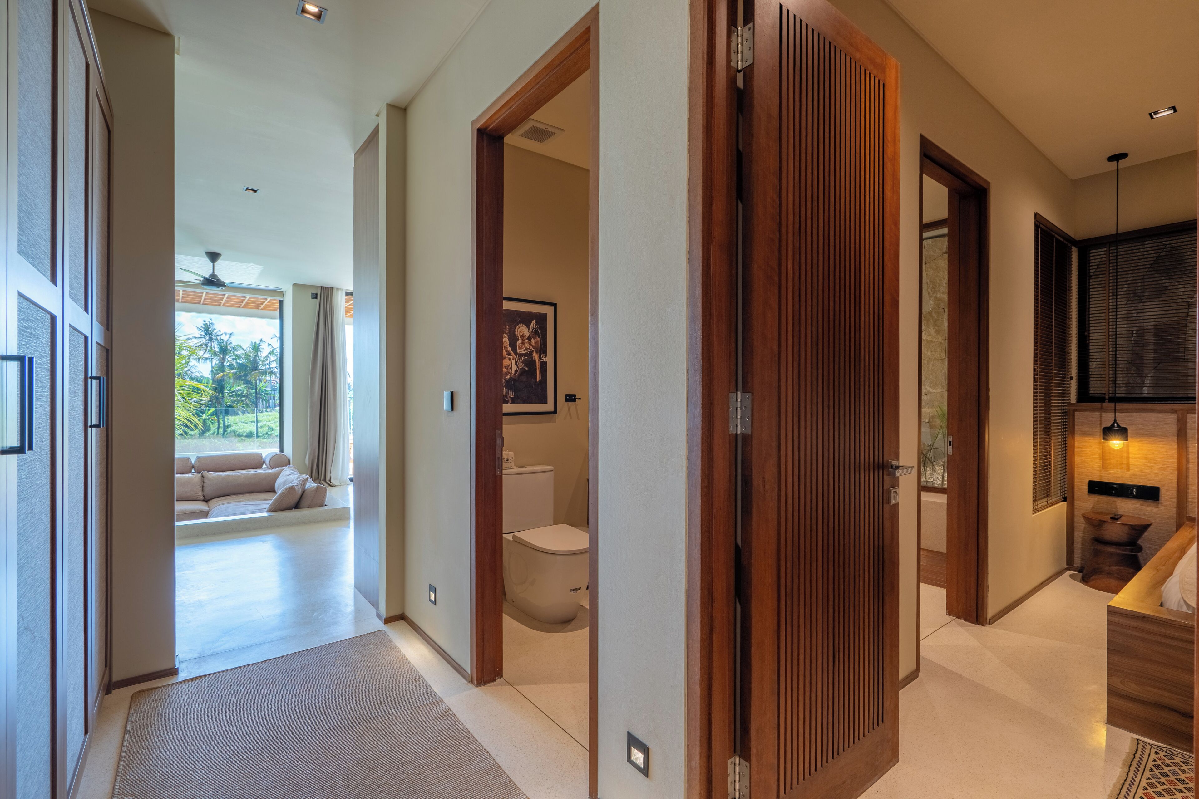 Un interior moderno con un pasillo que conduce a una sala de estar y un baño.