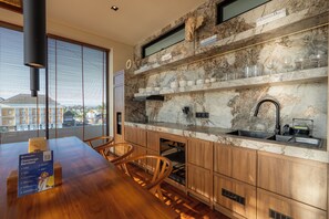 Eine moderne Küche mit Marmorarbeitsplatten, Holzschränken und einem Essbereich mit einem Holztisch und Stühlen.