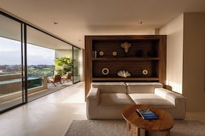 A modern living room with a sofa, a coffee table, and a wooden shelf with decorative items. - Sore Escape Tumbak Bayuh by Betterplace (Canggu)