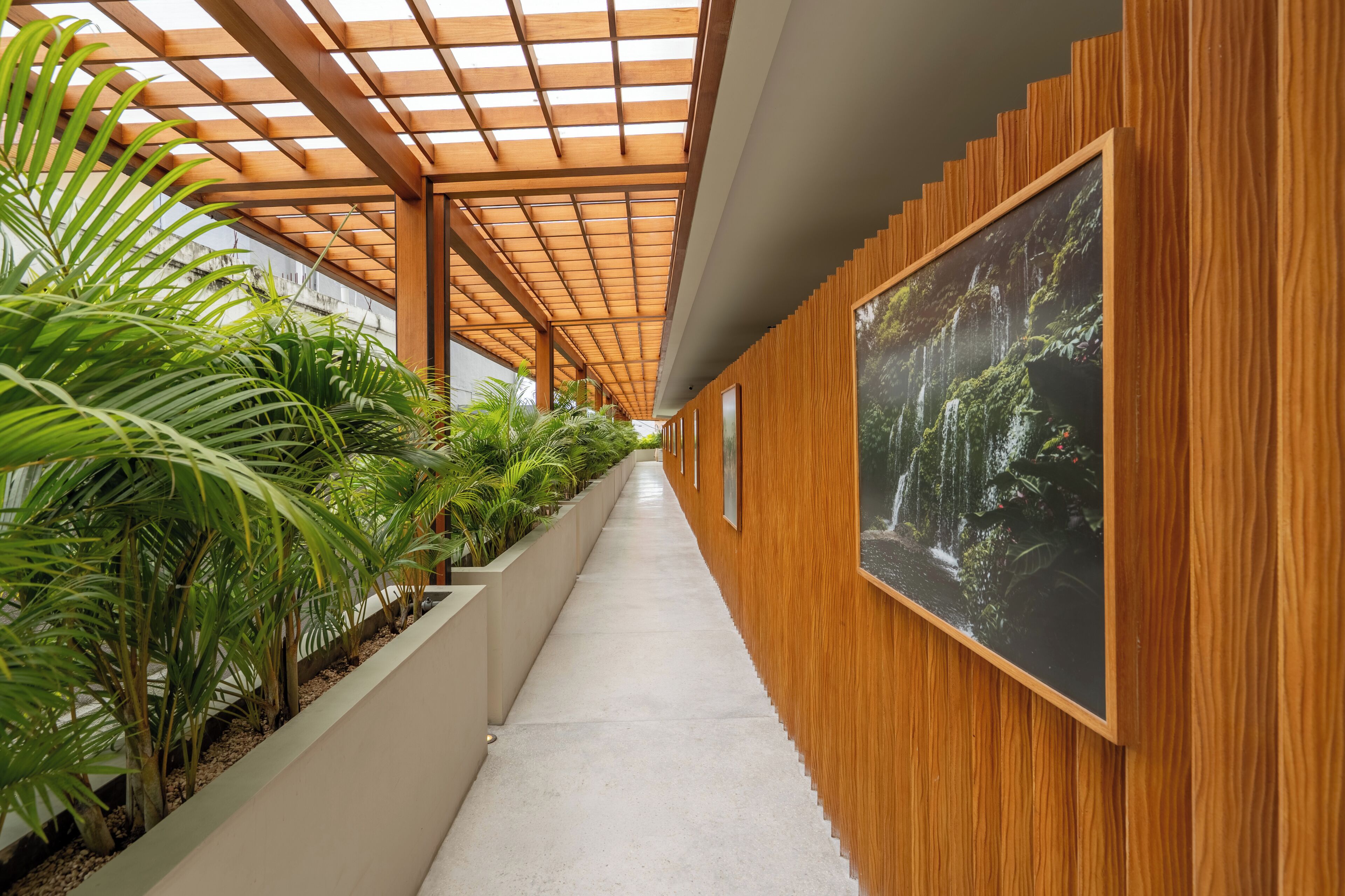 A corridor with a wooden ceiling, concrete floor, and wooden walls with framed pictures.