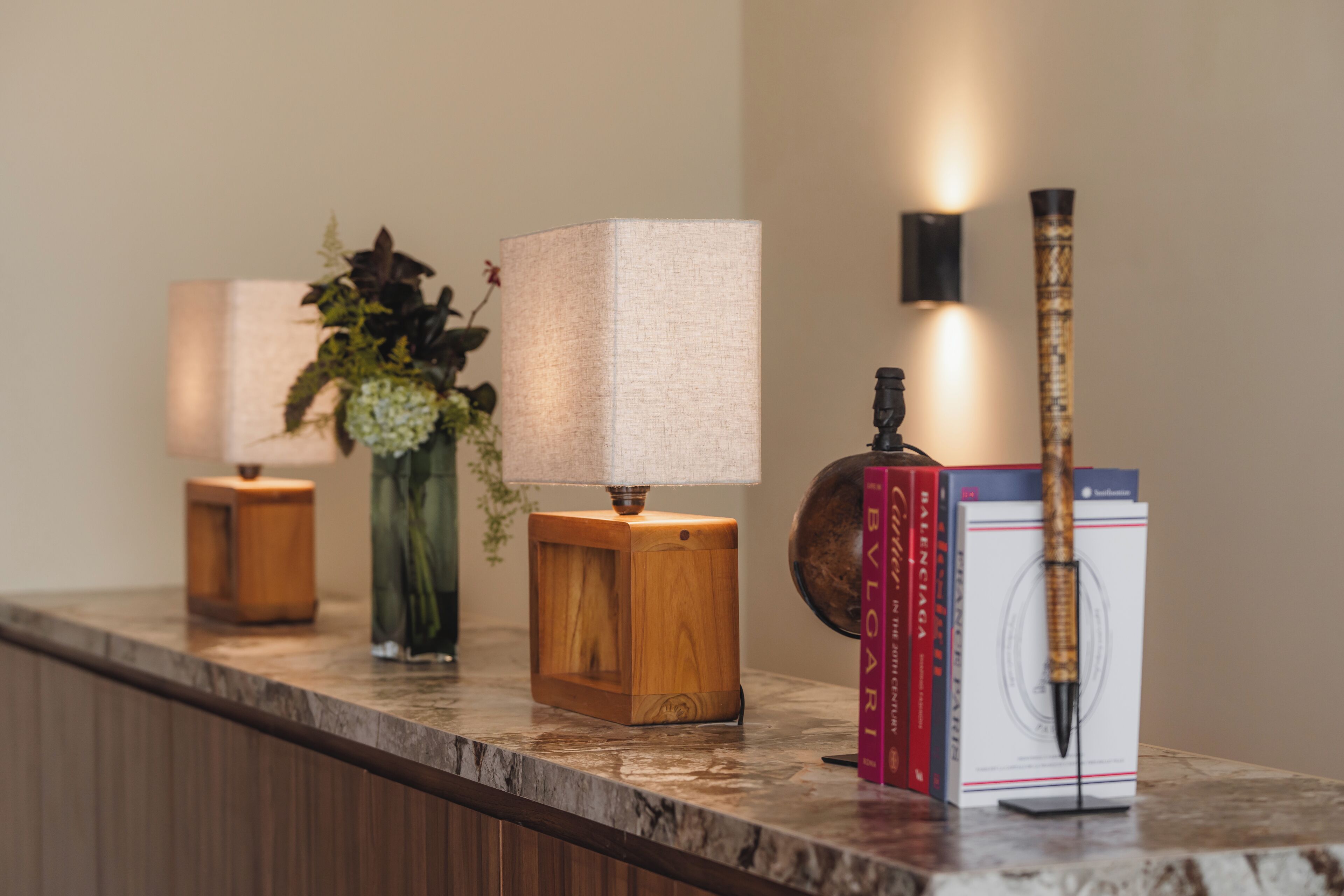 A marble countertop with a lamp, a vase with flowers, and a book.