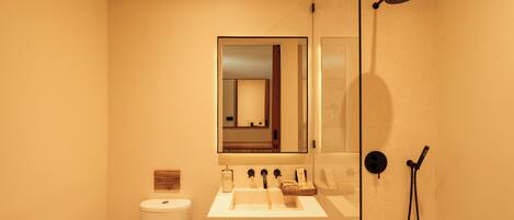 Un baño moderno con lavamanos, espejo, inodoro y ducha.