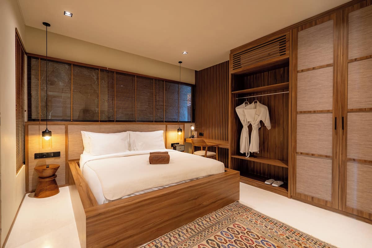 Ein modernes Schlafzimmer mit einem Holzbett, Nachttischlampen, einem Kleiderschrank und einem großen Fenster mit Jalousien.