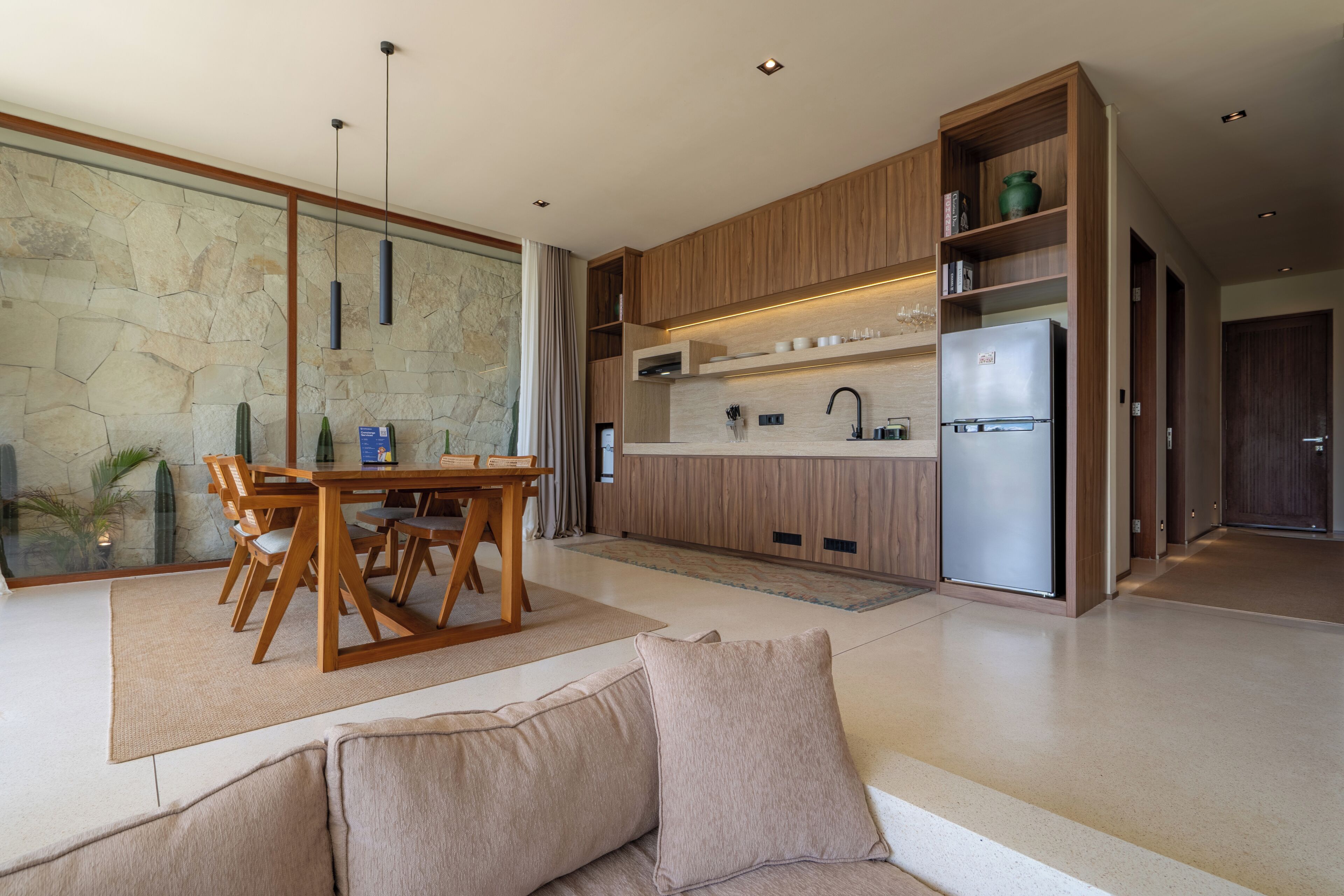 A modern kitchen with wooden cabinetry, a built-in refrigerator, and a dining area with a table and chairs.