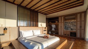 Une chambre avec un grand lit, une tête de lit en bois, des étagères intégrées et une cheminée.