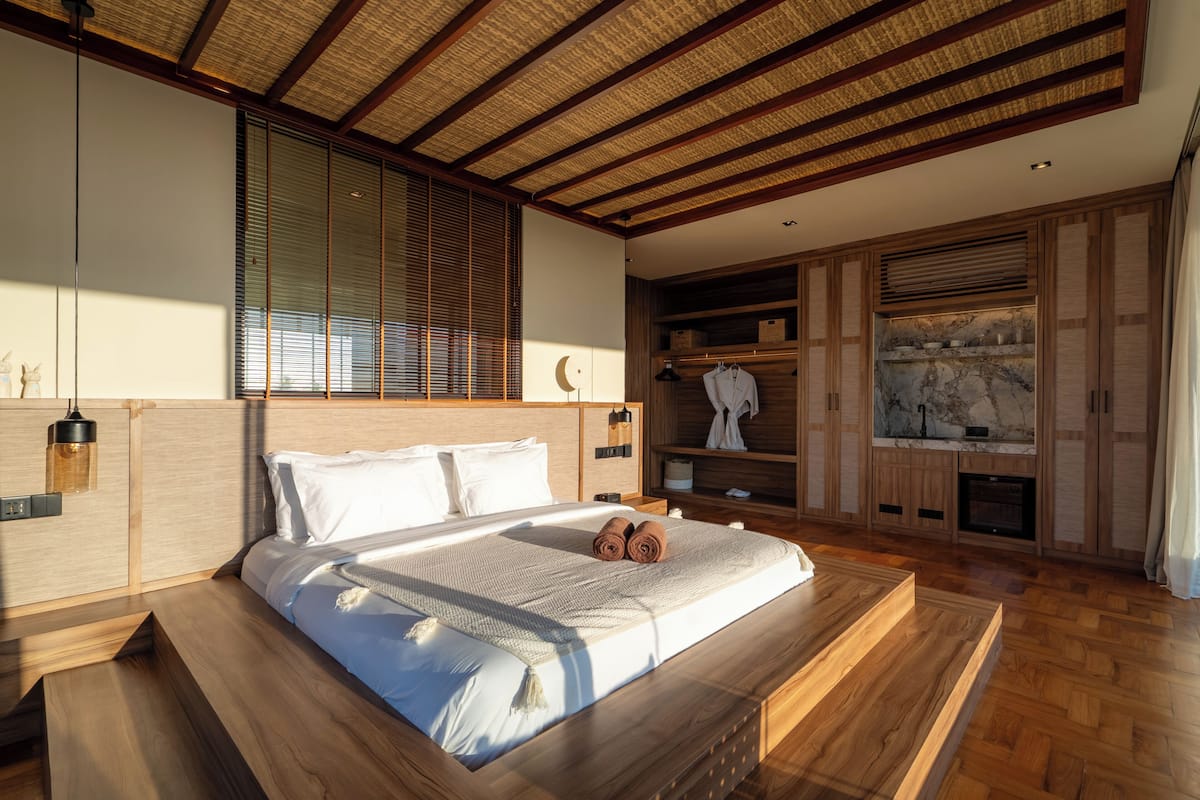 Ein Schlafzimmer mit einem großen Bett, einem Holzkopfende, integrierten Regalen und einem Kamin.