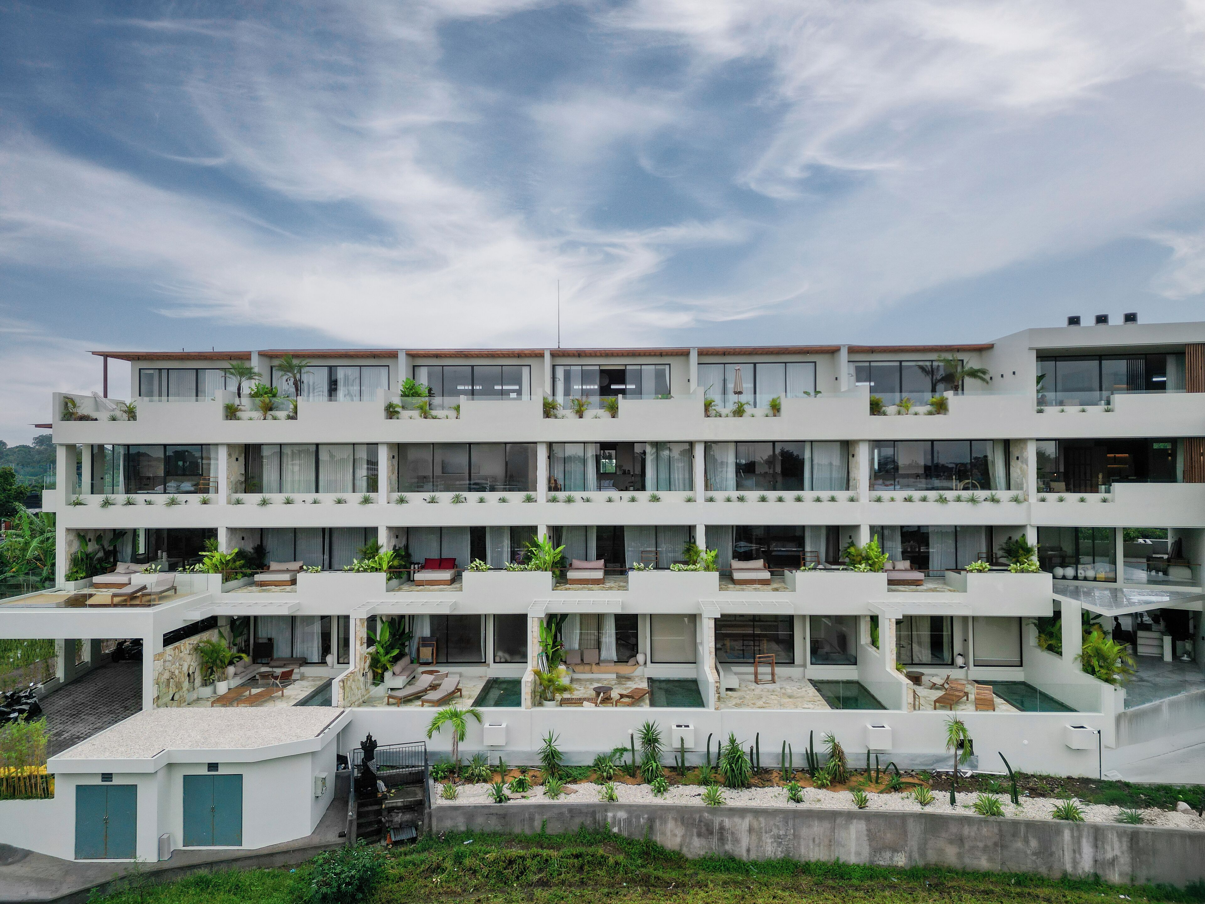 A multi-story building with balconies, outdoor seating, and a swimming pool.
