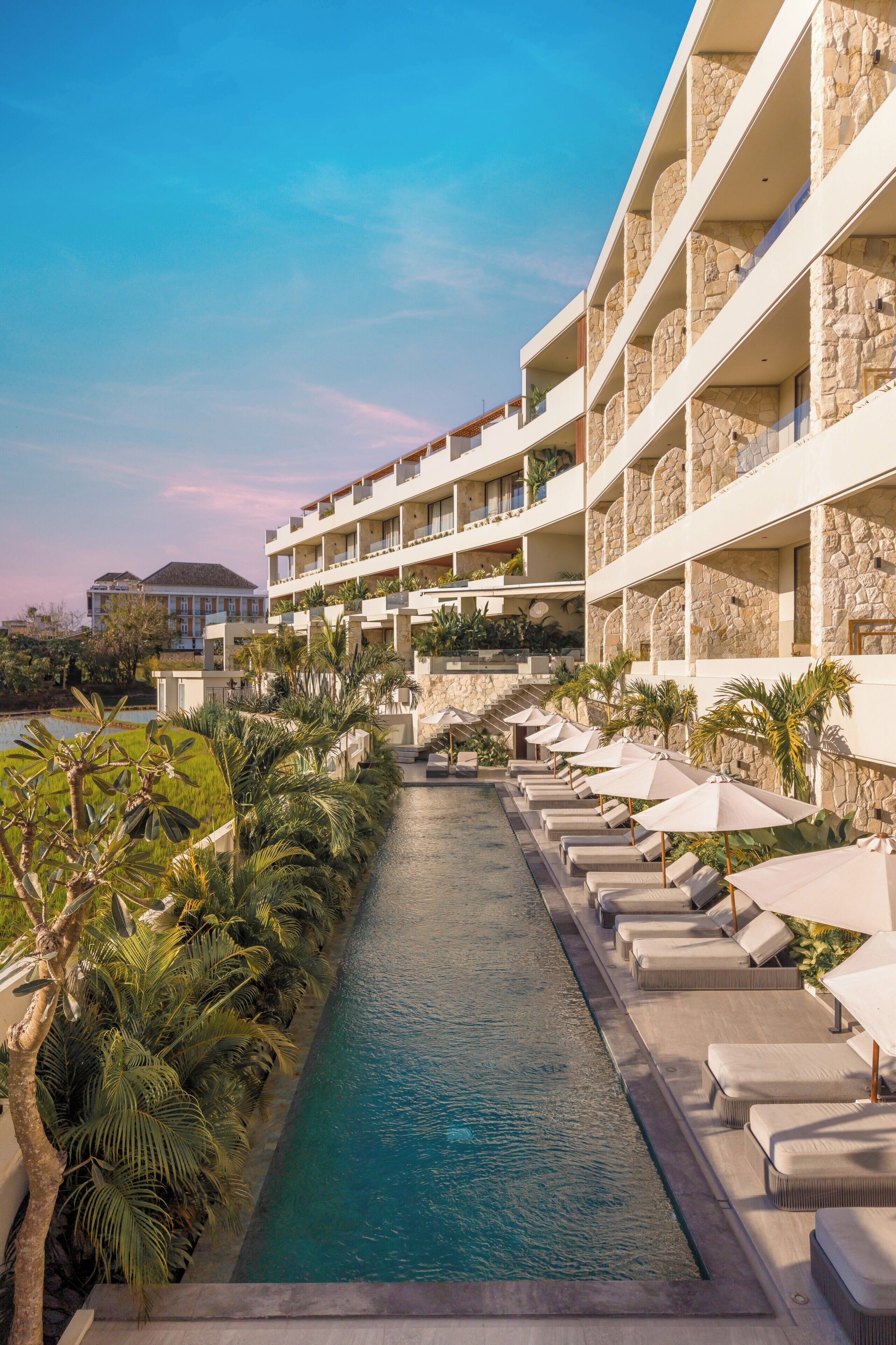 Un hotel con piscina, sillones de descanso y fachada de piedra.