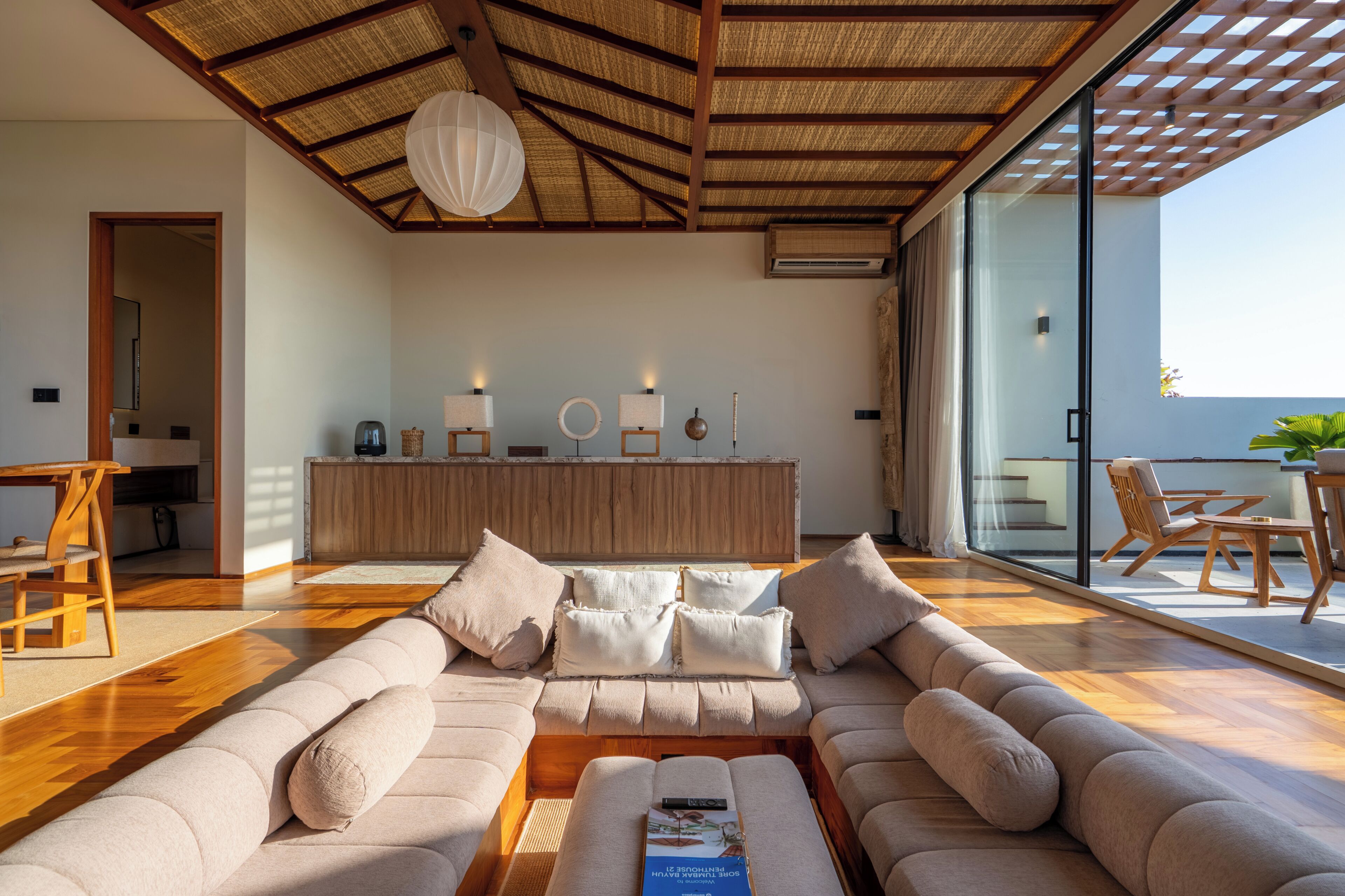 A modern living room with a large sectional sofa, a wooden coffee table, and a dining area with a table and chairs.