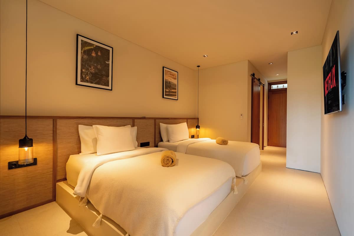 Ein Hotelzimmer mit zwei Betten, einem Fernseher und einem gerahmten Bild an der Wand.