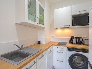 Een koelkast, een vaatwasser, kookgerei, borden en bestek