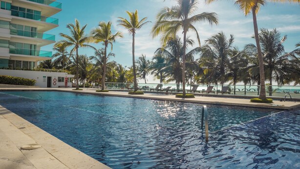 Ein Pool mit Palmen und einem modernen Gebäude im Hintergrund.